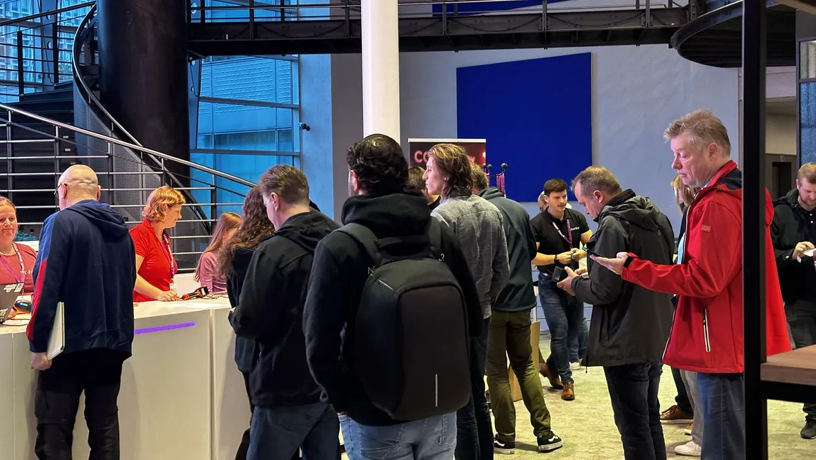 Professional conference attendees gathered around a booth, engaging with representatives in a modern exhibition hall.