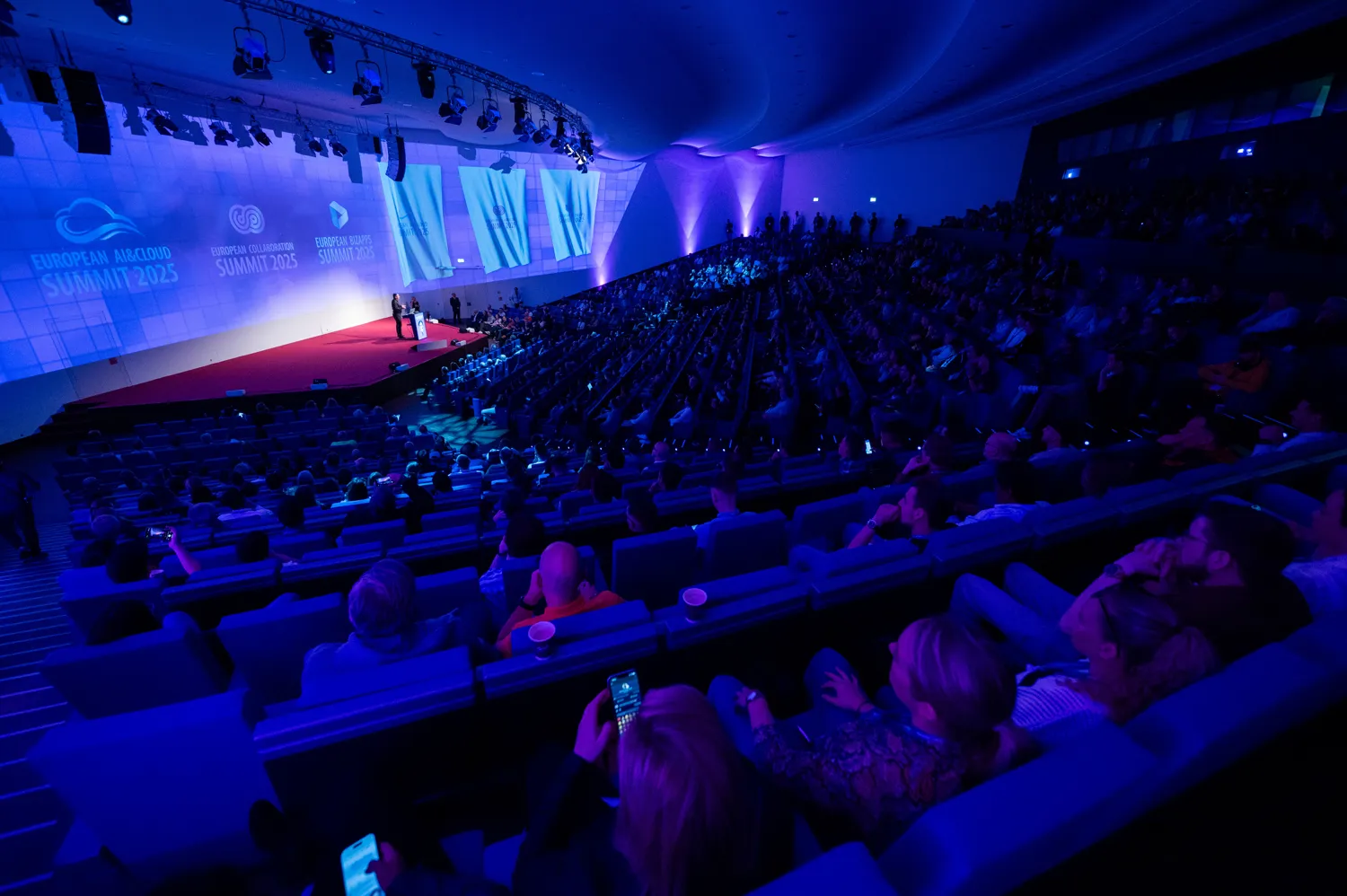 A full conference hall under blue stage lighting