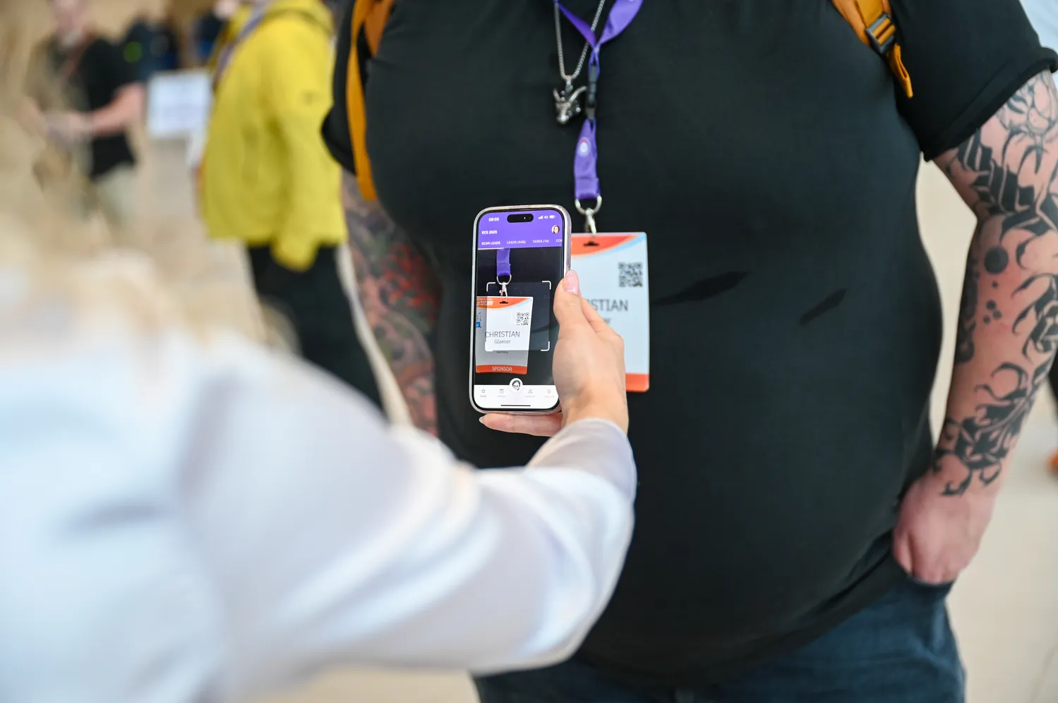 An attendee with a lanyard holding a smartphone