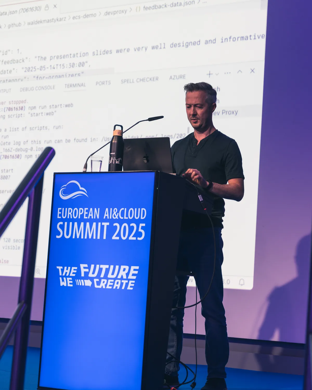A conference speaker at a podium with summit branding behind him during a technology event.