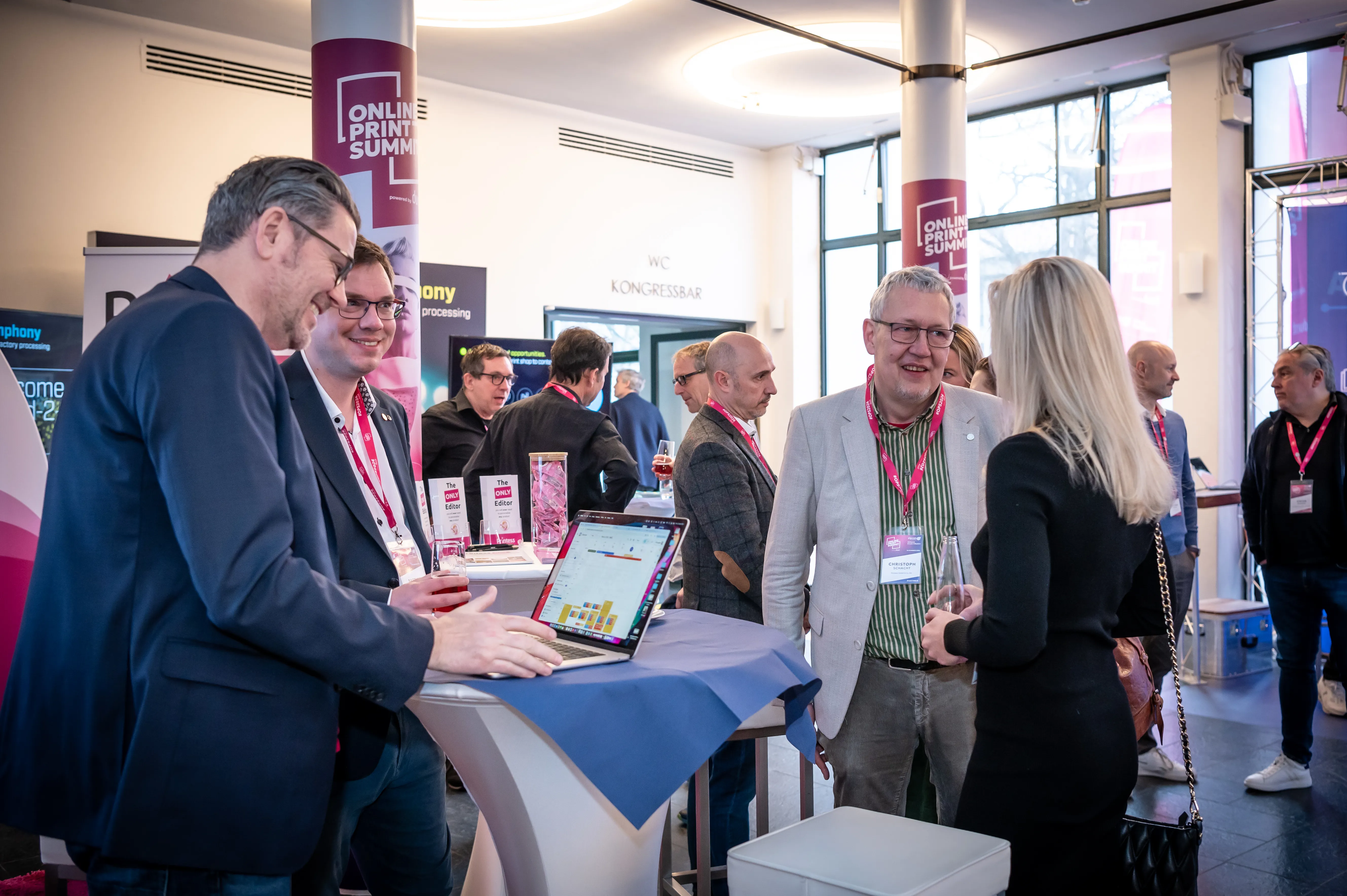 Zwei Teilnehmende im Gespräch an einem Partnerstand des Online Print Summit