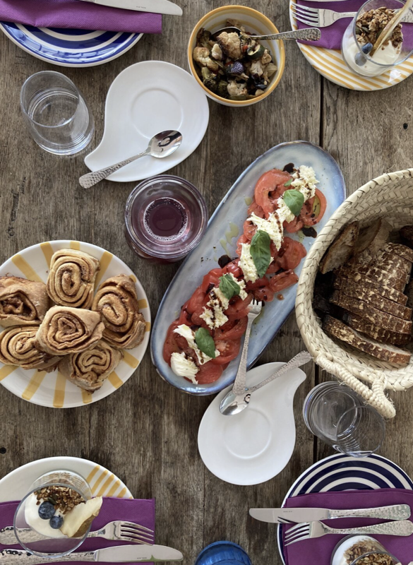 Breakfast table with pastries, tomato salad, berries and place settings in the GenussGarten