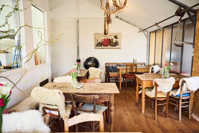 Warm dining room with wooden tables set for a shared meal