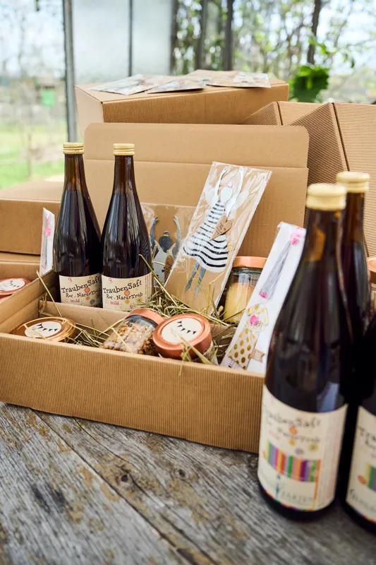 Geschenkbox mit Produkten aus der Gartenküche auf einem Holztisch.