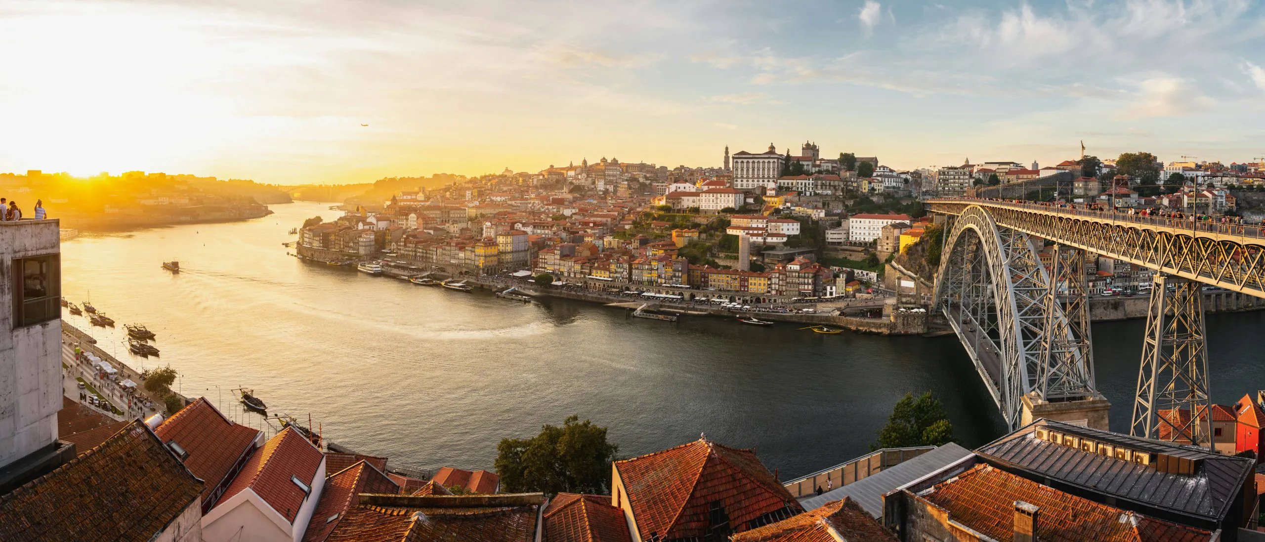 Evening riverfront cityscape in Porto with traditional buildings and the Dom Luís I Bridge